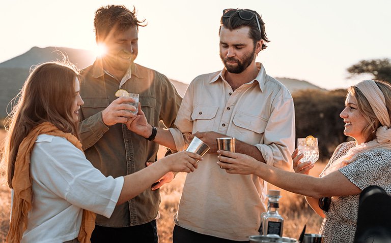 A group of people enjoying the sunset with drinks after a safari game drive