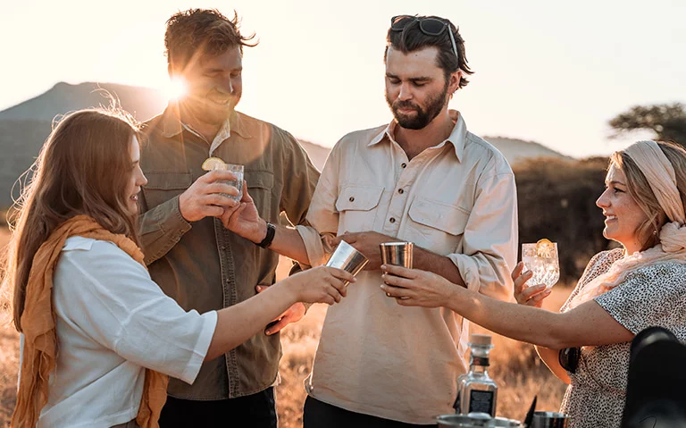 A group of people enjoying the sunset with drinks after a safari game drive